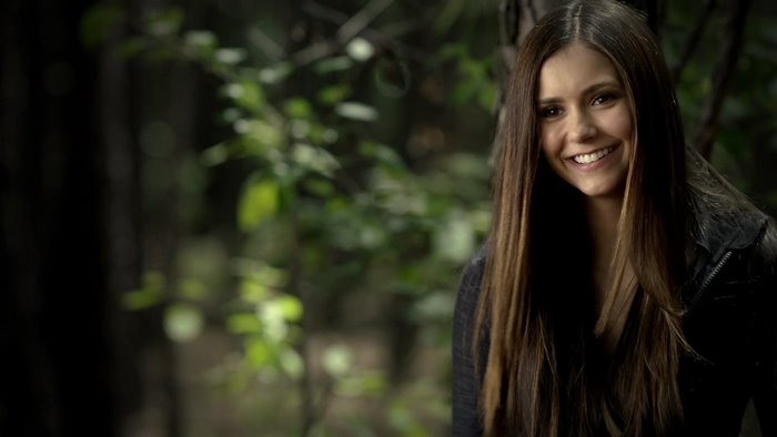 Nina Dobrev smiling in a forest