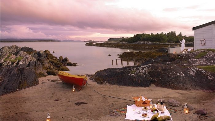 Picnic on a beach with a rowboat and a person in a robe