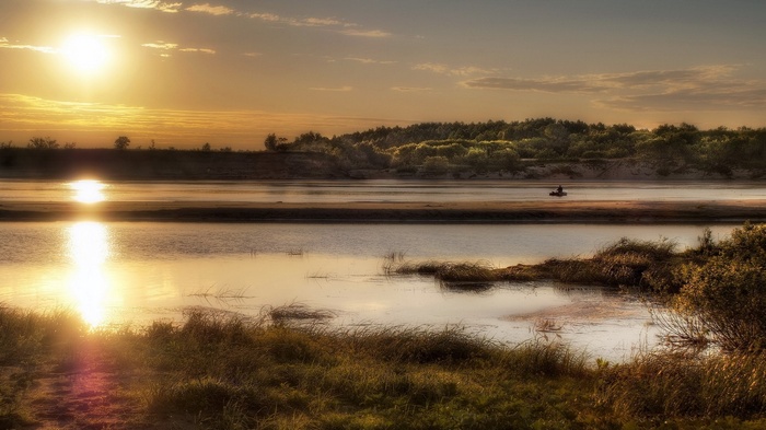 Sunset over a river with a lone kayaker