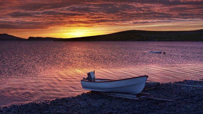 Boat on a rocky shore at sunset