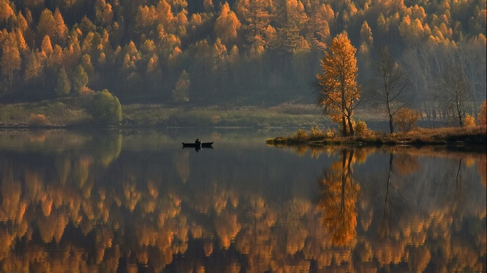 Person in a boat on a lake with autumn trees
