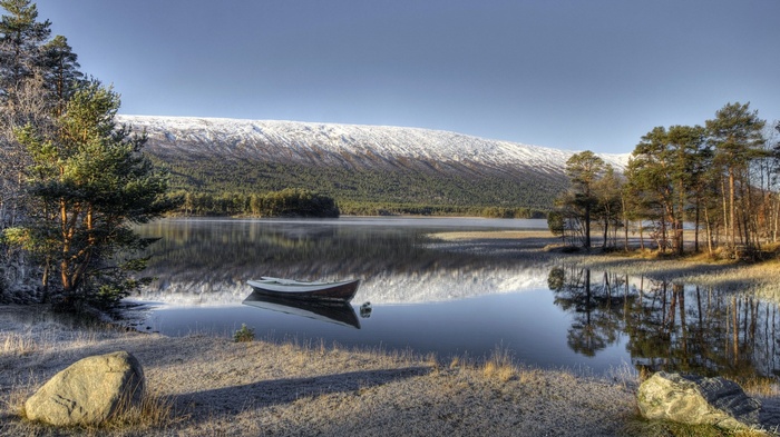 Boat on a calm lake with snow-capped mountains