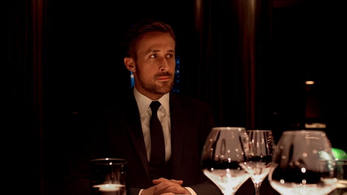 Ryan Gosling in a suit at a table