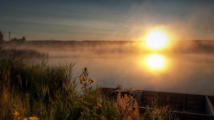 Sunrise over a misty lake with a boat