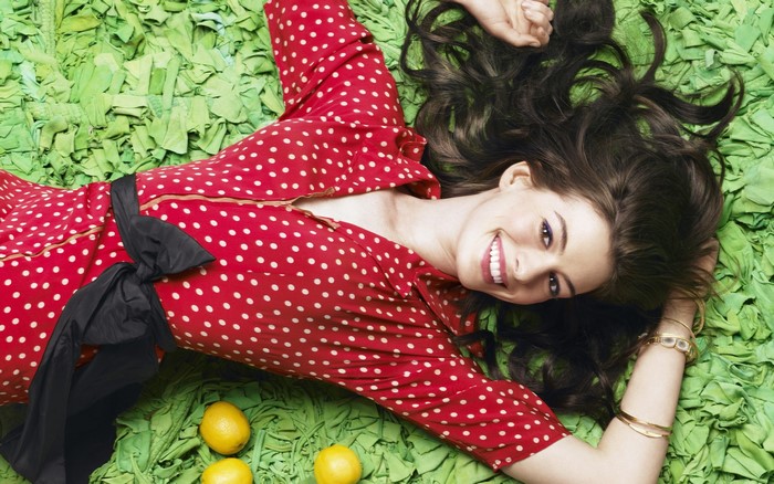 Anne Hathaway lying on green fabric with lemons