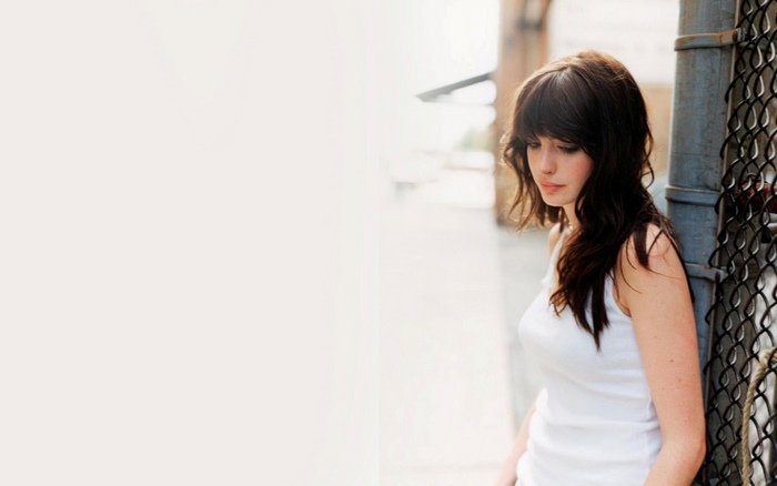 Anne Hathaway leaning against a fence
