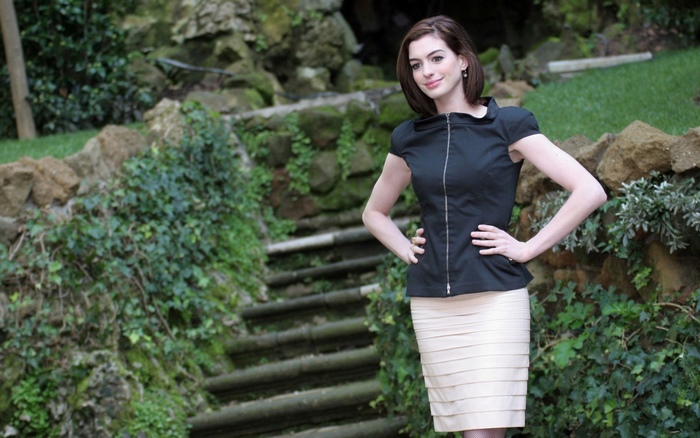 Anne Hathaway in a black top and beige skirt