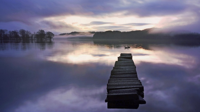 Wooden pier on a misty lake at dawn