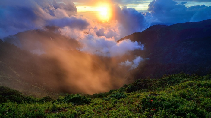 Sunrise over misty mountains with green foreground