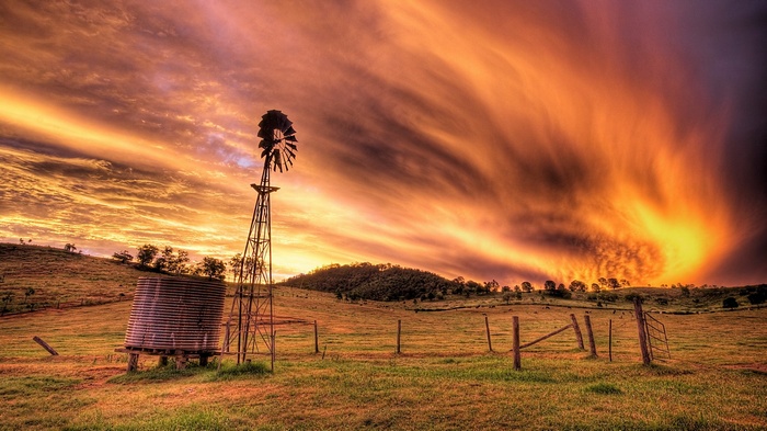 Windmill and water tank at sunset