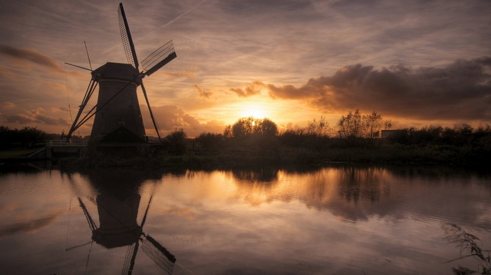 Windmill reflected in water at sunset