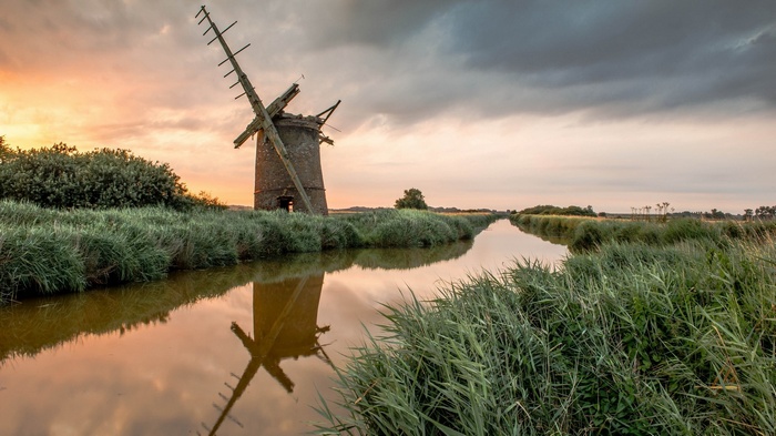 Old windmill by a canal at sunset