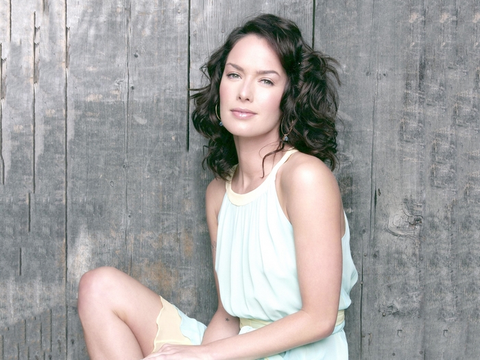 Lena Headey sitting against a wooden wall