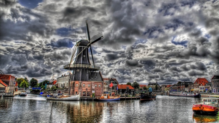 Windmill and boats on a canal under a cloudy sky