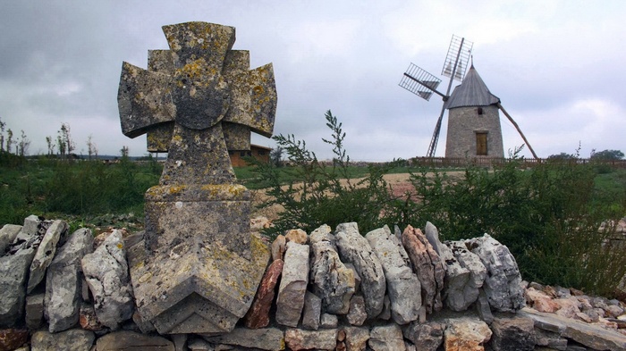 Stone cross and windmill in a field