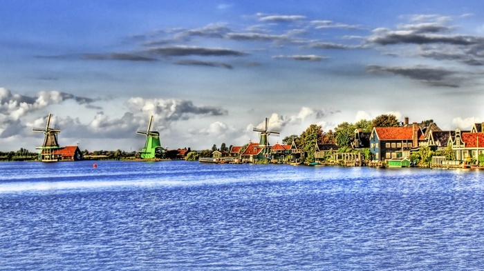Windmills and houses by a river