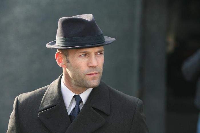 Jason Statham wearing a fedora and coat