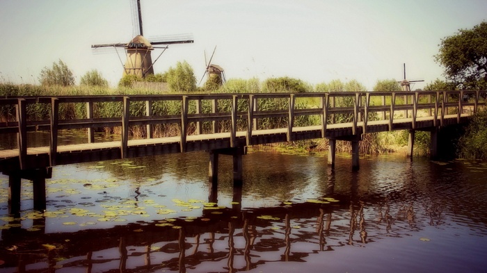 Wooden bridge over water with windmills in the background