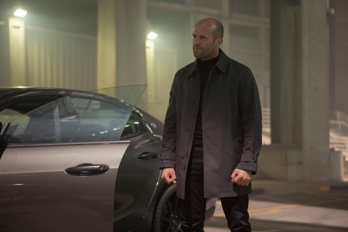 Jason Statham standing next to a car
