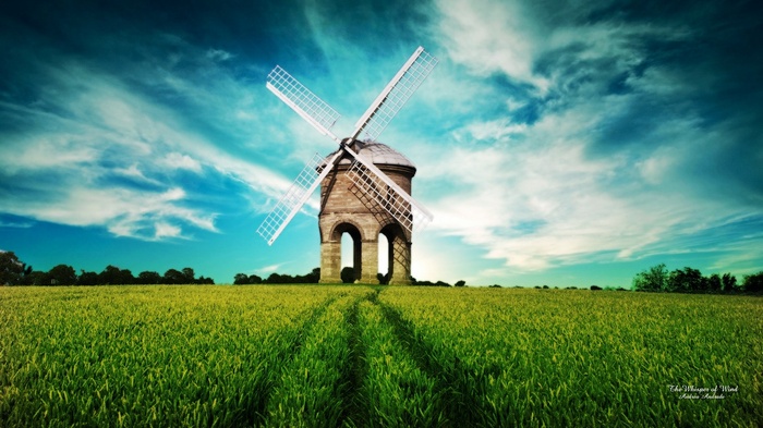 Windmill in a green field under a cloudy sky