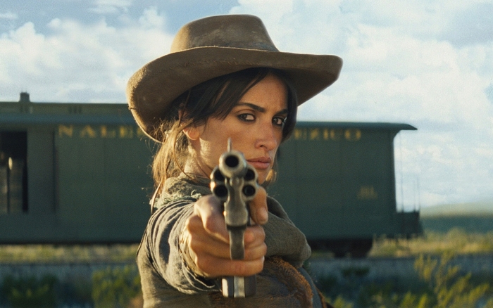 Penélope Cruz with a gun in front of a train