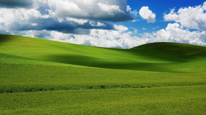 Rolling green hills under a cloudy blue sky