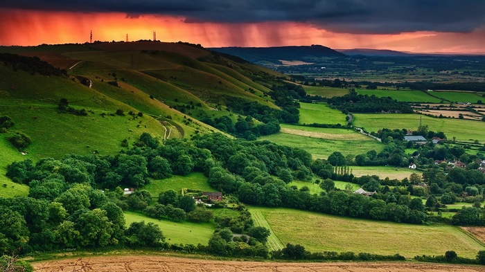Rolling green hills with a dramatic sunset sky