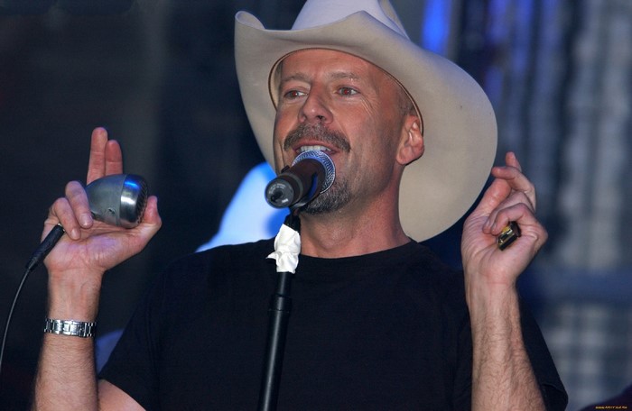 Bruce Willis wearing a cowboy hat singing