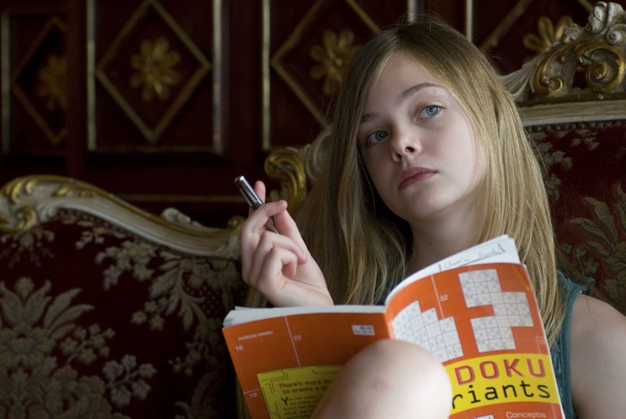 Elle Fanning holding a pen and a puzzle book