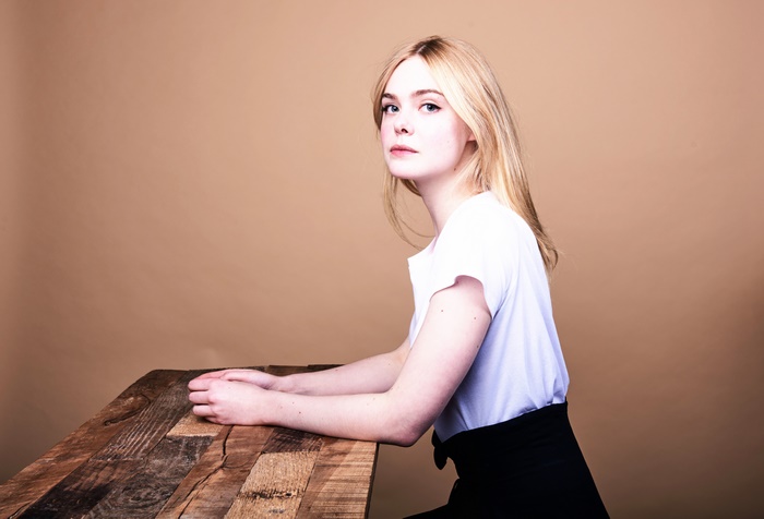 Elle Fanning sitting at a wooden table