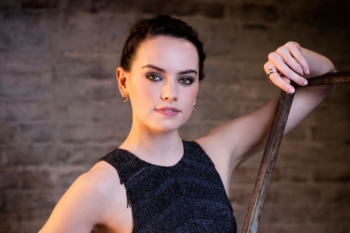 Daisy Ridley posing against a brick wall