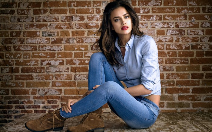 Irina Shayk sitting in front of a brick wall