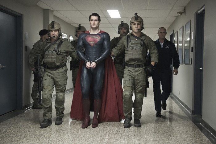 Superman from DC Comics in handcuffs with military escort