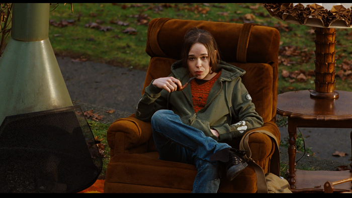 Ellen Page sitting in a chair with a pipe