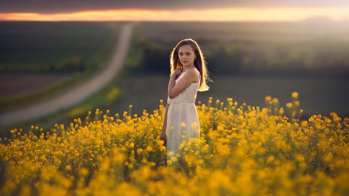 Woman in white dress in a field of yellow flowers