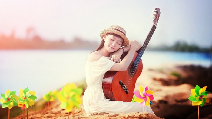 Girl with guitar on beach with pinwheels