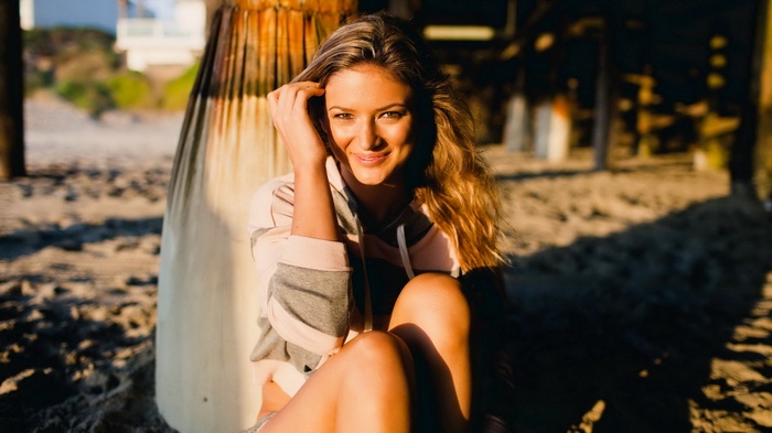 Woman sitting on a beach near a pier