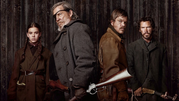 Four people with rifles in front of a wooden wall
