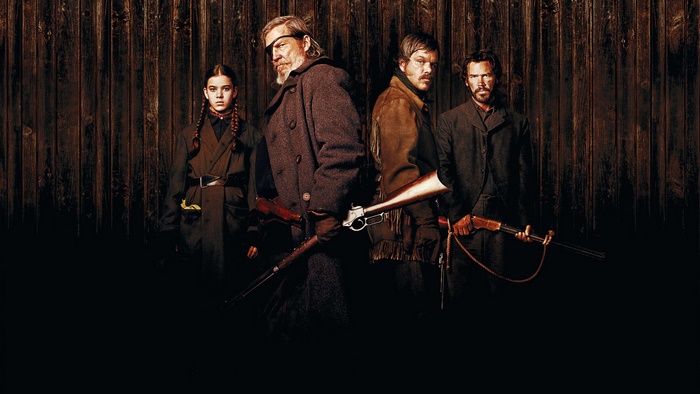 Four people with guns in front of a wooden wall