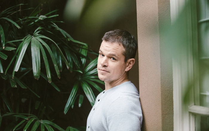 Matt Damon leaning against a wall with plants