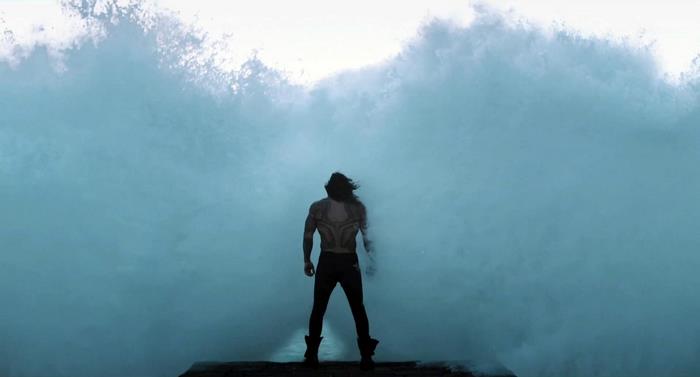 Aquaman from DC Comics standing in front of a large wave