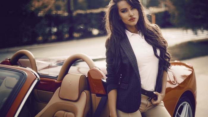 Woman in blazer leaning on a red convertible car