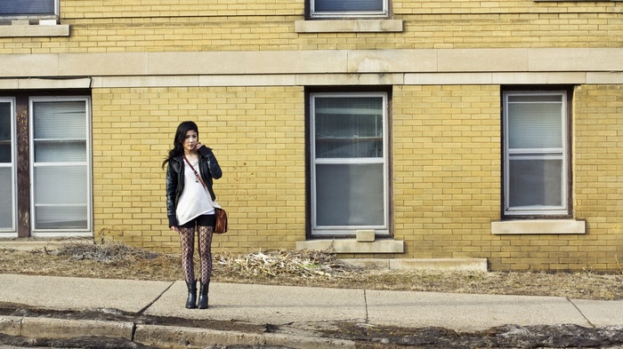 Woman in black jacket and fishnet stockings standing outside