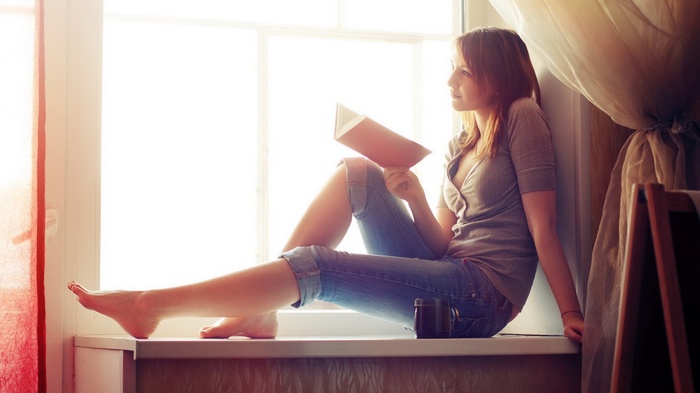 Woman reading a book by the window