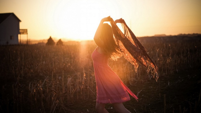 Woman in pink dress with scarf at sunset