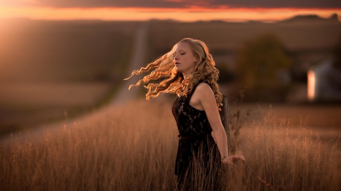 Woman with curly hair in a field at sunset