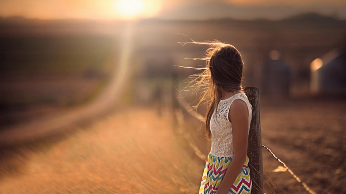 Girl in white top and colorful skirt looking away