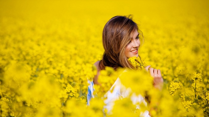 Young woman in a field of yellow flowers
