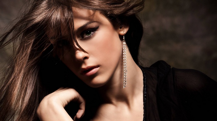Woman with long brown hair and dangling earring