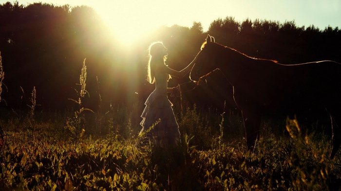 Woman in a dress with a horse at sunset